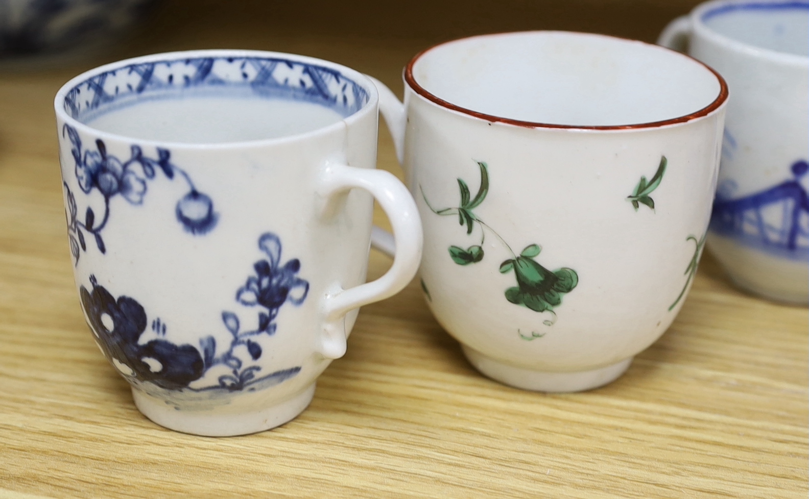 Seven various English porcelain coffee cups, including two Bristol enamelled with green floral sprays, two Bow painted in underglaze blue with a bird in a Chinese garden, and three Worcester/Bow in underglaze blue.